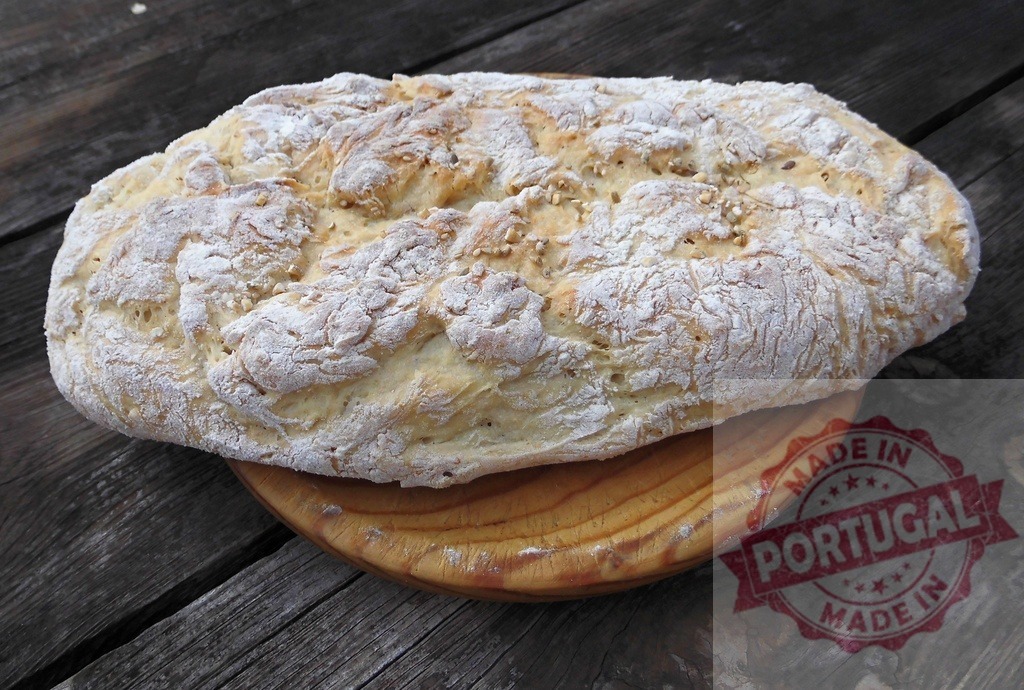 Homemade artisan rustic bread loaf on wooden table | Freshly baked bread loaf topped with flour on a dark wood surface creating a rustic scene - Realisiert mit Pictrs.com