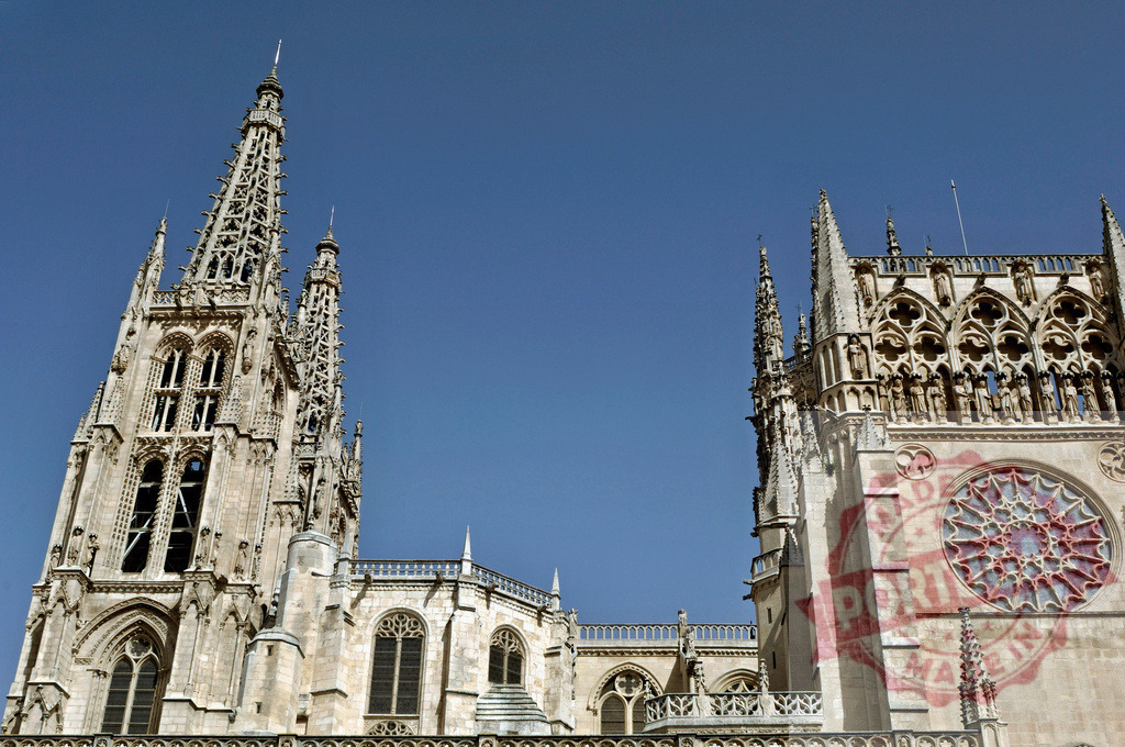 Burgos Cathedral displaying elaborate Gothic spires against blue sky. Spain - Burgos | Burgos Cathedral, a UNESCO World Heritage site, features ornate Gothic architecture and towering spires - Realized with Pictrs.com