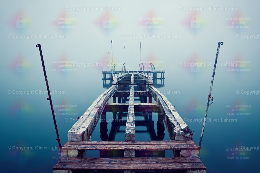 Die Brücke im Nebel | Eine alte Landungsbrücke die zum Teil demontiert ist, steht im spiegelglatten Wasser und ist umgeben von dichten Nebel