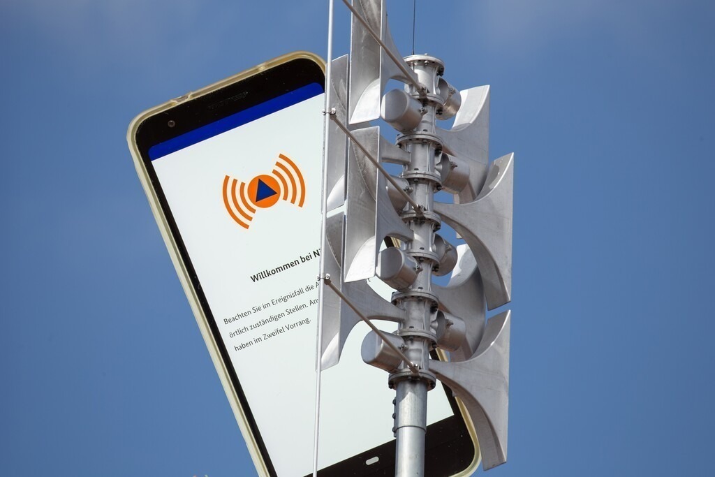 Bundesweiter Warntag 11. September: Sirene und Nina-App | (Fotomontage) Nahaufnahme einer Sirene, daneben die geöffnete Warn-App NINA auf einem Smartphone - Realisiert mit Pictrs.com
