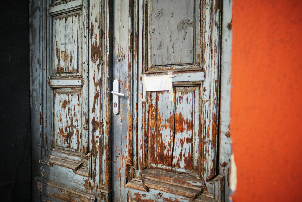 Alte hölzerne Eingangstüre mit einer orangen Hauswand | Wien, Austria - April 01, 2021: entlang der Wiener Gürtel Straße; Alte hölzerne Eingangstüre mit einer orangen Hauswand. - Realisiert mit Pictrs.com