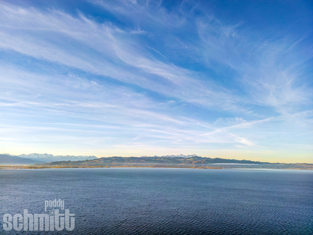 Bodenseee am frühen Morgen mit Blick in die Schweiz | Der Bodensee zeigt sich am frühen Morgen von seiner besonders stillen und atmosphärischen Seite. Der Blick über das ruhige Wasser reicht bis in die Schweiz, während das sanfte Morgenlicht die Landschaft in eine besondere Stimmung taucht. - Realisiert mit Pictrs.com
