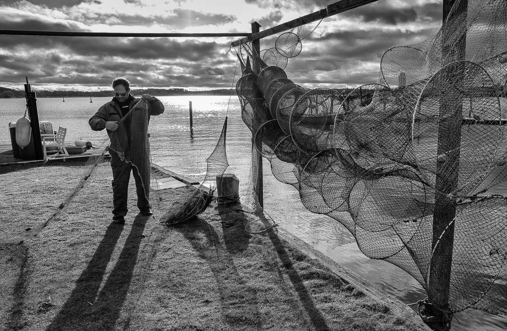 fischer-2020-012 | Der Fischer Matthias Nanz aus Schleswig ist einer der letzten Berufsfischer an der Schlei. Die Fischerei war früher prägend für den Schleswiger Stadtteil Holm, in dem Matthias Nanz lebt. Das Bild zeigt ihn bei der Reparatur seiner Reusen. - Realisiert mit Pictrs.com