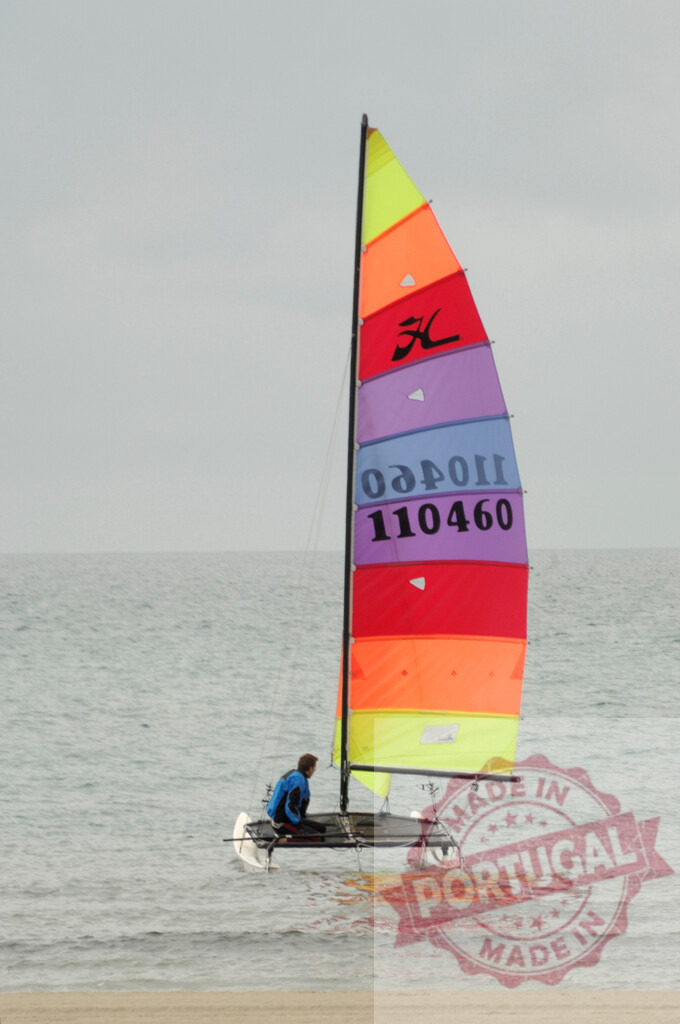 Lone yachtsman sailing small catamaran with colorful sail | Yachtsman sailing small catamaran with colorful sail in the sea - Realisiert mit Pictrs.com