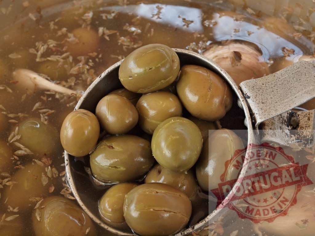 Green olives in brine with spices and ladle | Green cracked olives marinating in seasoned brine with a metal ladle - Realisiert mit Pictrs.com
