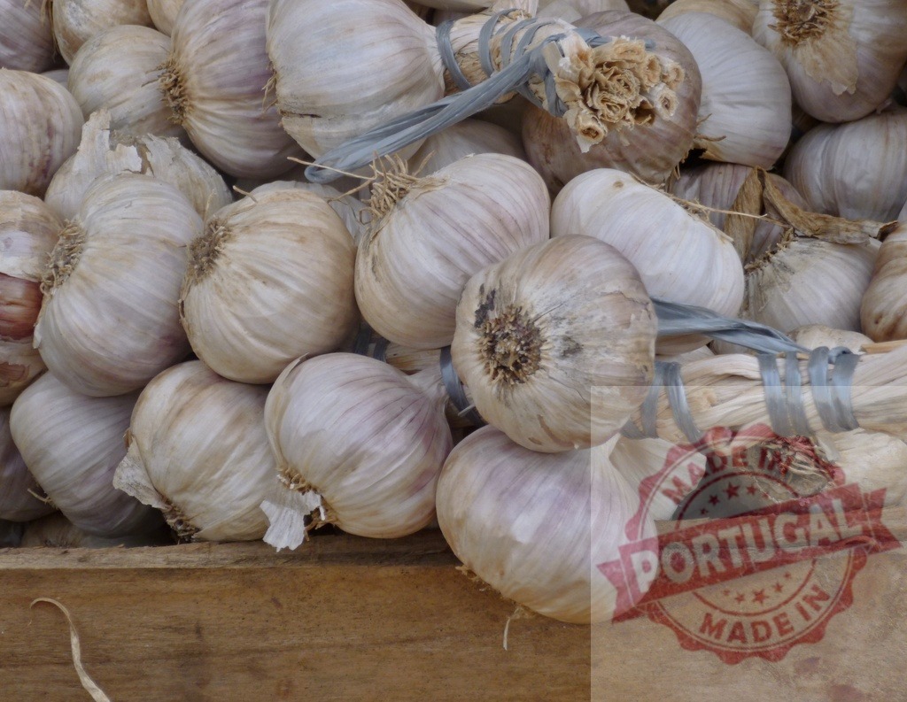 Garlic bulbs bundles for sale at market | Garlic bulbs bundled together available for purchase in a rustic wooden crate - Realisiert mit Pictrs.com
