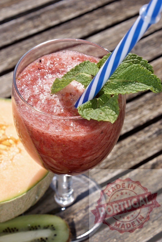 Refreshing fruit smoothie with mint and straw on wooden table | Red fruit smoothie with mint and a striped straw, resting on a wooden surface beside fruit - Realisiert mit Pictrs.com