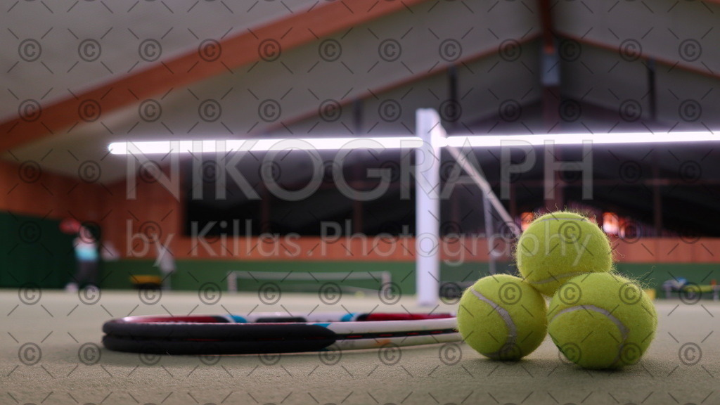 Tennisballpyramide | Eine Tennisballpyramide neben einem Tennisschläger in der Tennishalle.