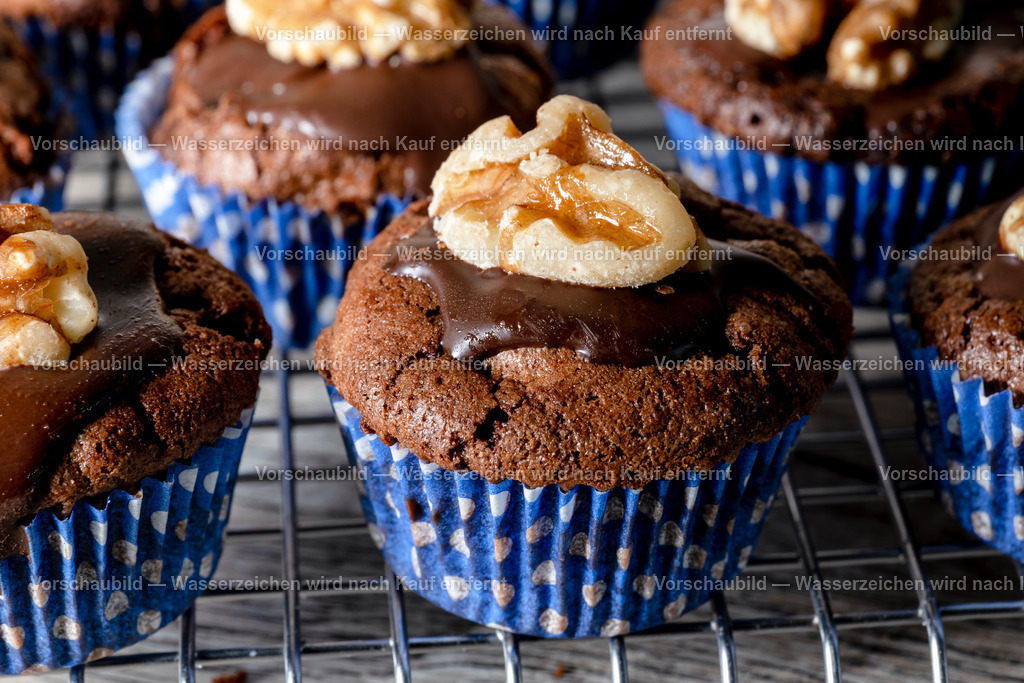 Nahaufnahme mehrere frisch gebackene Wallnussmuffins auf einen Kuchengitter  | Nahaufnahme mehrere frisch gebackene Wallnussmuffins auf einen Kuchengitter in blauer Muffinform. - Realisiert mit Pictrs.com