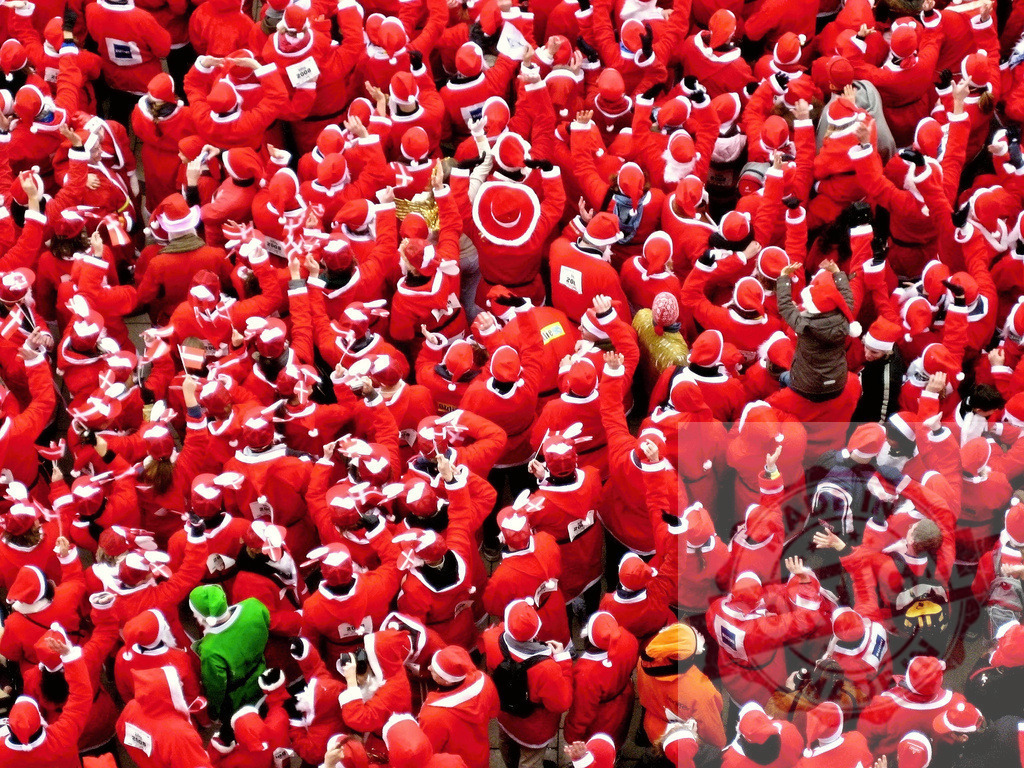 Crowd of Santas waving during a Christmas gathering in a city square | Many people wearing Santa Claus costumes are celebrating Christmas all together in a city square, creating a festive atmosphere - Realized with Pictrs.com