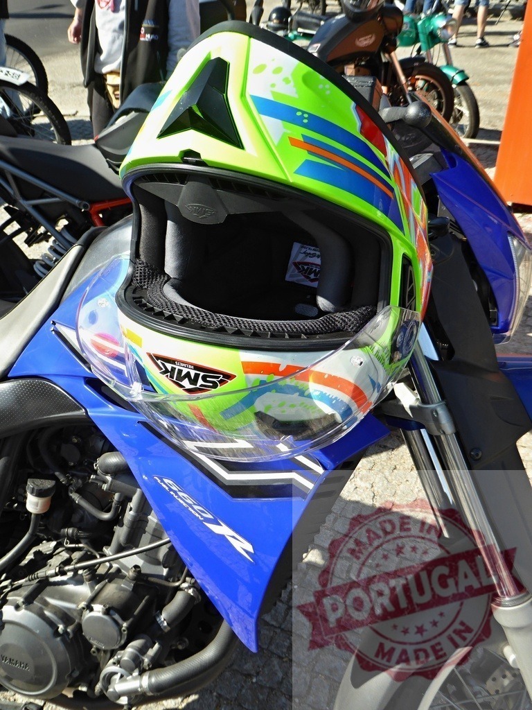 Colorful motocross helmet resting on a blue Yamaha motorcycle | Vibrant motocross helmet sits on a blue Yamaha motorcycle, ready for action - Realized with Pictrs.com