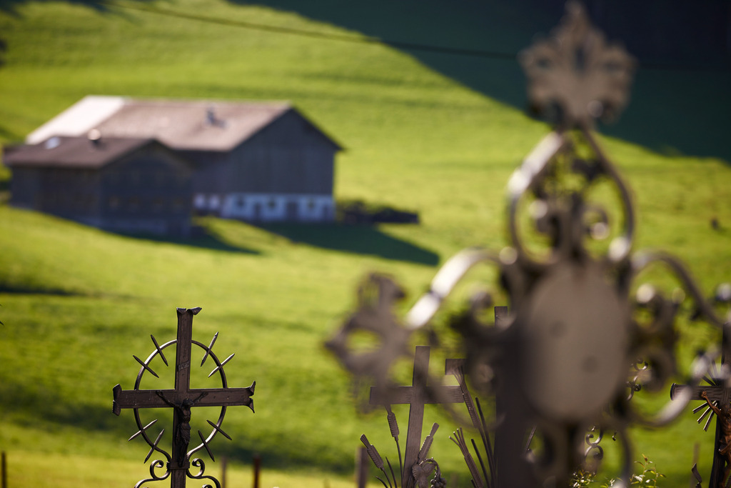 schmiedeeisernes Kreuz | Schwarzenberg, Austria - August 04, 2014: Blick vom Friedhof mit Kreuzen, auf eine Wiese mit Bauernhaus. - Realisiert mit Pictrs.com