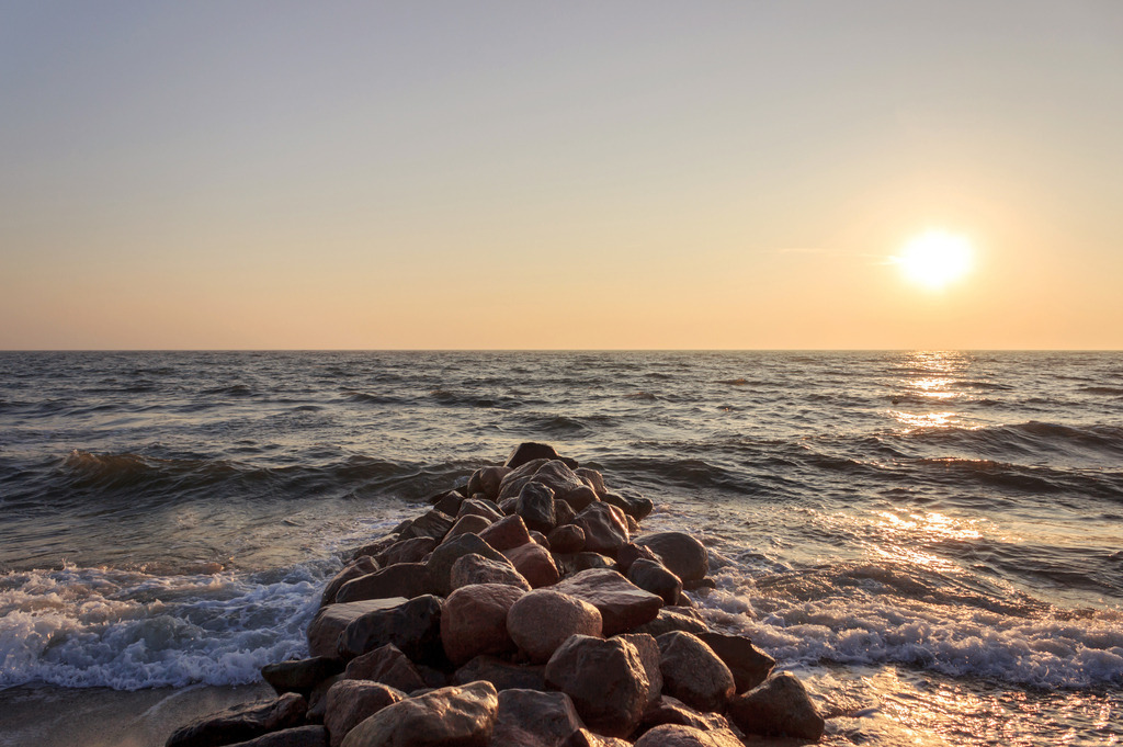 Wandbild: Sonnenaufgang am Meer | Dieses Wandbild im Querformat zeigt einen schönen Sonnenaufgang über der Ostsee. Im Vordergrund ragt eine Steinmole ins Meer, der dem Wandbild eine schöne Tiefe gibt.  - Realisiert mit Pictrs.com