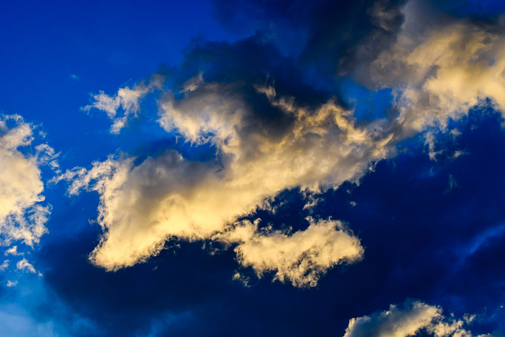 Dramatisches Wolkenspiel am Himmel | Mächtige, goldgelb angestrahlte Quellwolken heben sich kontrastreich von einem tiefblauen Himmel ab und kündigen die wechselhafte Dynamik eines Sommertages an. Das späte Sonnenlicht taucht die zerklüfteten Wolkenformationen über Garmisch-Partenkirchen in ein warmes, magisches Leuchten, während dunklere Schattenseiten Spannung erzeugen. Eine ausdrucksstarke Naturaufnahme, die die Kraft, Weite und emotionale Tiefe sommerlicher Himmelsszenarien eindrucksvoll einfängt. - Realisiert mit Pictrs.com