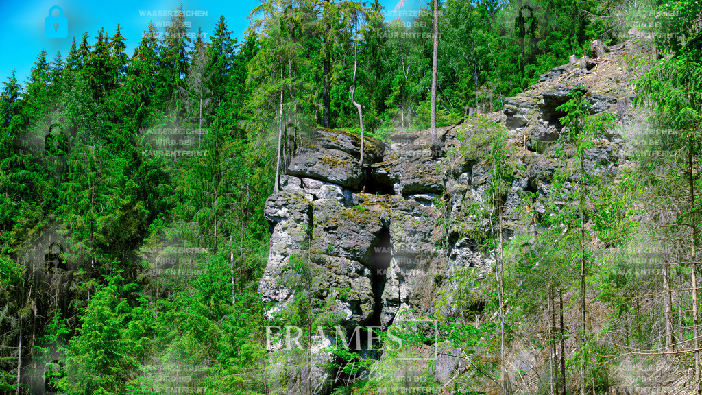 Klippe im Meer aus Grün | Das Foto zeigt eine markante Klippe aus weißem und grauem Gestein, die mitten im Wald steht und sich deutlich von der umliegenden, dichten Vegetation abhebt. Die Felsformation wirkt wie ein heller Akzent in einem Meer aus Grün, da die Bäume und das Blattwerk den Kontrast zum hellen Gestein verstärken. Die Aufnahme betont sowohl die natürliche Struktur und Schichtung des Felsens als auch die besondere Wirkung, die durch das Zusammenspiel von Stein, Licht und Waldumgebung entsteht. Die Szene vermittelt ein Gefühl von Ruhe und Ursprünglichkeit und zeigt einen außergewöhnlichen geologischen Blickfang innerhalb der Waldlandschaft. - Realisiert mit Pictrs.com