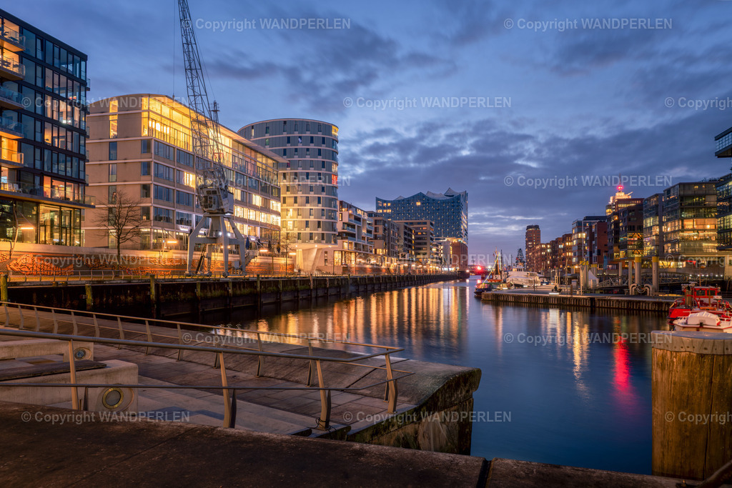 Sandtorhafen in eienr Sommernacht | Am Abend zeigt sich der Sandtorhafen in Hamburg von seiner faszinierendsten Seite: Moderne Architektur und lebendige Stadtentwicklung verschmelzen zu einem einzigartigen Bild. Die erleuchteten Gebäude, die stillen Kräne und die Boote am Kai spiegeln sich im Wasser und schaffen eine Atmosphäre, die den Charme der Stadt perfekt einfängt. - Realisiert mit Pictrs.com