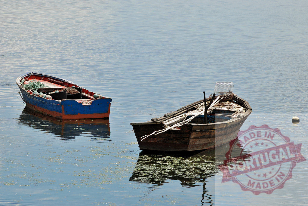 Two fishing boats floating calmly on blue water. Galicia - Spain | Two old fishing boats floating on still water, showing reflections and a sense of tranquility - Realized with Pictrs.com