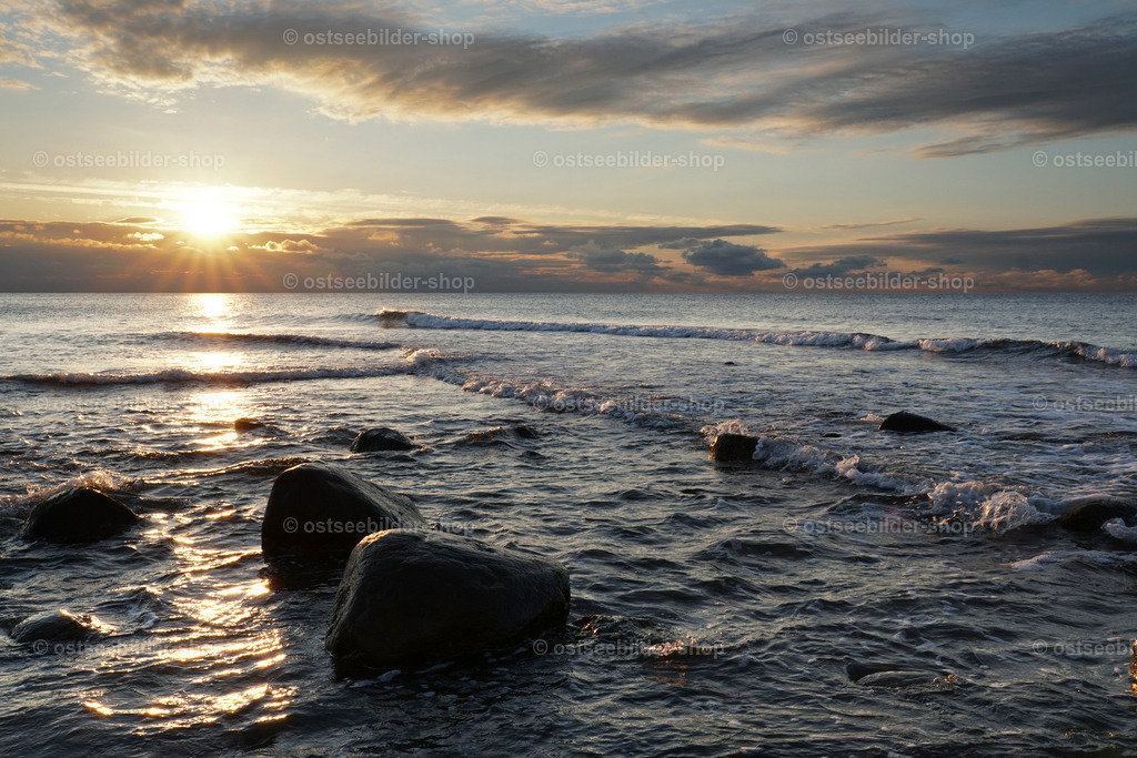 Kreuzwellen im Abendlicht | Das Bild zeigt eine riffähnliche Sandbank mit Findlingen abends am Ostseeufer. Flache Wellen aus zwei verschiedenen Richtungen laufen hier aufeinander zu und kreuzen sich. 