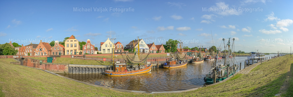 Greetsiel in Ostfriesland Panorama | Panoramaaufnahme des Hafens von Greetsiel in Ostfriesland an einem schönen Sommertag. Der historische Hafen ist über 600 Jahre alt und wird regelmäßig von 25 Krabbenkuttern angesteuert. In Greetsiel ist damit die größte Krabbenkutterflotte Ostfrieslands zuhause. - Realisiert mit Pictrs.com