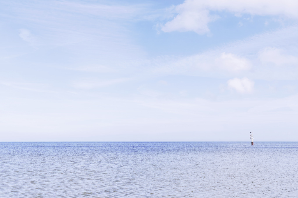 Orientierungspunkt im Meer – Ruhe unter blauem Himmel | Dieses Motiv zeigt die weite, ruhige Fläche des Meeres unter einem klaren blauen Himmel. Ein einzelner Orientierungspunkt ragt aus dem Wasser und setzt einen feinen, minimalistischen Akzent in der offenen Landschaft. Die leichten Wolken und das sanfte Licht verstärken die Atmosphäre von Stille, Klarheit und maritimer Weite. Die Komposition wirkt reduziert, hochwertig und strahlt eine tiefe Ruhe aus. Als Wandbild erhältlich auf Acrylglas und weiteren hochwertigen Materialien.