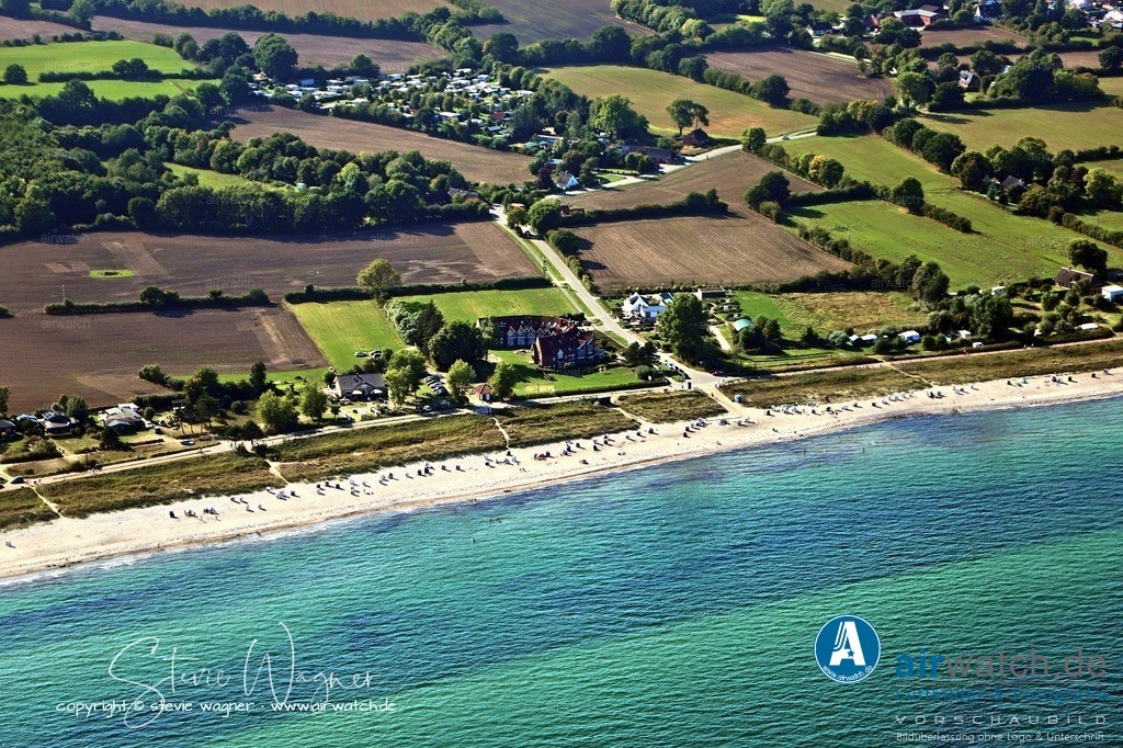 Luftbild Kronsgaard Strand - Der Kronsgaard Strand ist ein etwa 3 Kilometer langer Naturstrand | Der Kronsgaard Strand ist ein etwa 3 Kilometer langer Naturstrand an der freien Ostsee in Schleswig-Holstein, zwischen Falshöft und Maasholm gelegen. Der feinsandige Strand gilt als einer der schönsten in der Region und ist besonders familienfreundlich – das flache Wasser und die Überwachung durch die DLRG in den Sommermonaten sorgen für Sicherheit. Der Strand ist zertifiziert als Lifeguarded Beach und wird von April bis Oktober bewacht. Für Erholungssuchende gibt es Strandkorbvermietung, gastronomische Angebote wie das Strandcafé „Lieblingsplatz“ und Imbisswagen, sowie einen extra ausgewiesenen Hundestrand. Der Zugang ist barrierearm.