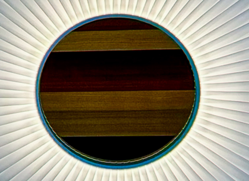 Wandbild Abstrall-Geometrie - Haptisches Holz- und Metall-Mandala | Dieses exklusive abstrakte Wandbild fasziniert durch eine meisterhafte Kombination aus kühler, urbaner Geometrie und der organischen Wärme von feinem Holz. Die perfekt symmetrischen, radialen Linien laufen hypnotisch auf ein kreisrundes Zentrum mit horizontaler Holzmaserung zu und erzeugen eine beeindruckende visuelle Tiefe. Fotograf Robert Steinke fängt das Zusammenspiel aus metallischen Reflexionen, haptischen Strukturen und grafischer Perfektion in gestochen scharfer Premium-Qualität ein. Ein absolut progressiver Blickfang für minimalistische Wohnräume, stilvolle Lofts oder moderne Büros, die ein harmonisches und zugleich kraftvolles Design-Statement vertragen. Perfekt als großformatiger Premium-Kunstdruck auf Alu-Dibond, Leinwand oder unter brillantem Acrylglas. - Realisiert mit Pictrs.com
