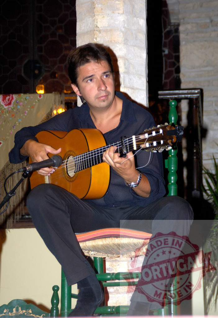 Spanish man playing flamenco guitar during live performance | Spanish man playing a classical guitar with a microphone capturing the sound during a performance - Realisiert mit Pictrs.com