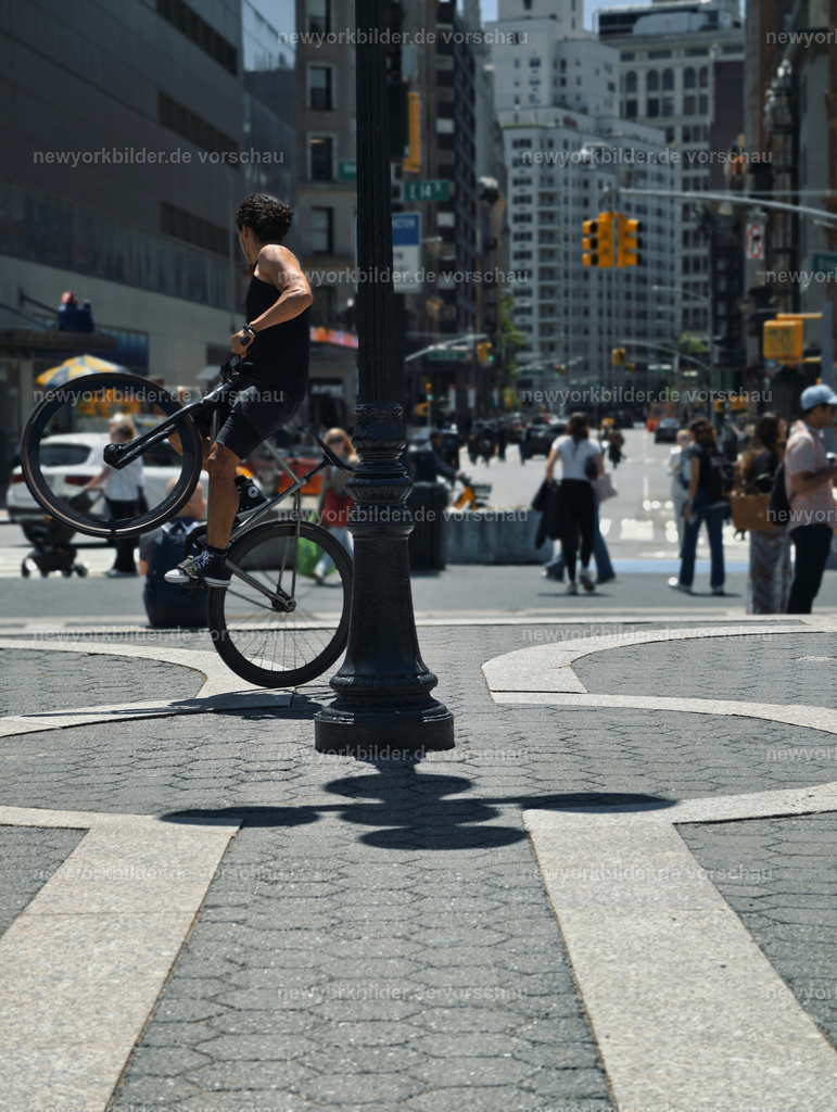 Union Square – Kunst, Bewegung und Sommerleben in New York | Ein sonniger Samstag am Union Square – die Luft ist erfüllt von Stimmen, Musik und dem Duft regionaler Produkte. Zwischen Marktständen und Künstlern, die ihre Werke präsentieren, zieht ein Radfahrer alle Blicke auf sich. Mit beeindruckenden Tricks verwandelt er den Platz in eine Bühne und zeigt, wie lebendig und kreativ New York ist. Menschen bleiben stehen, applaudieren, lachen und genießen den Augenblick, während die Stadt im Hintergrund pulsiert. Dieses Motiv erzählt von Freiheit, Bewegung und der Vielfalt, die den Union Square zu einem Treffpunkt für Kultur und Lebensfreude macht. Die Szene ist ein Spiegel der Metropole: dynamisch, bunt und voller Energie. Ein Bild, das den Sommer in New York einfängt – mit all seinen Facetten, von spontaner Kunst bis zum urbanen Rhythmus, der niemals endet.