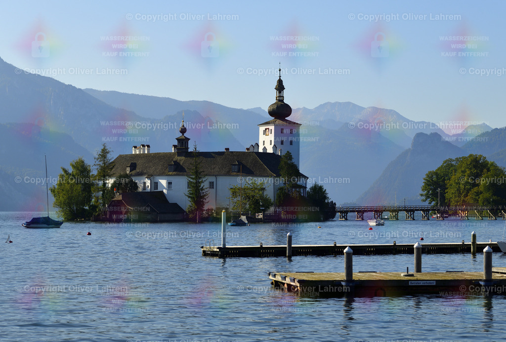 Das Orter Schloss im See | Das Schloss Ort liegt im Traunsee über das nur eine Brücke führt und im Hintergrund sieht man im Sommerlicht die Berge.