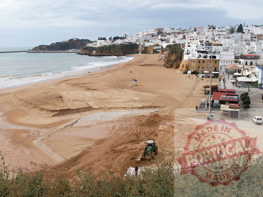 Tractor moving sand on Albufeira beach in Portugal | Albufeira Flood - discruction by weather problems Green tractor moving sand on a wide beach with white buildings in the background - Realisiert mit Pictrs.com