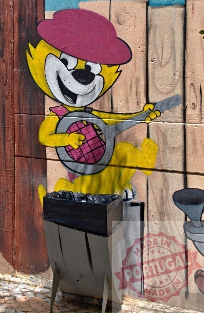 Top cat playing banjo painted on a wall | Cheerful cartoon cat playing banjo painted on a wall with a trash can in front - Realized with Pictrs.com