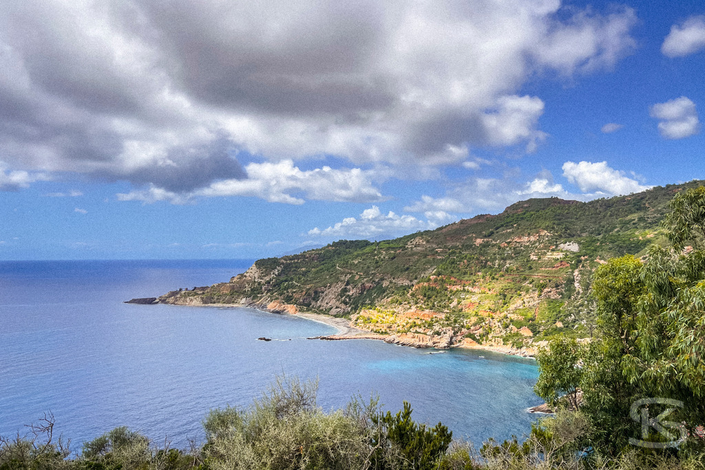 Wildes Elba: Panoramablick über die Küstenlandschaft auf das Mittelmeer – Wandbild | Panorama-Ausblick auf die hügelige Küstenlandschaft der Insel Elba mit typisch mediterraner Vegetation (Macchia) im Vordergrund und dem weiten, blauen Meer unter sommerlichen Wolkenformationen. - Realisiert mit Pictrs.com
