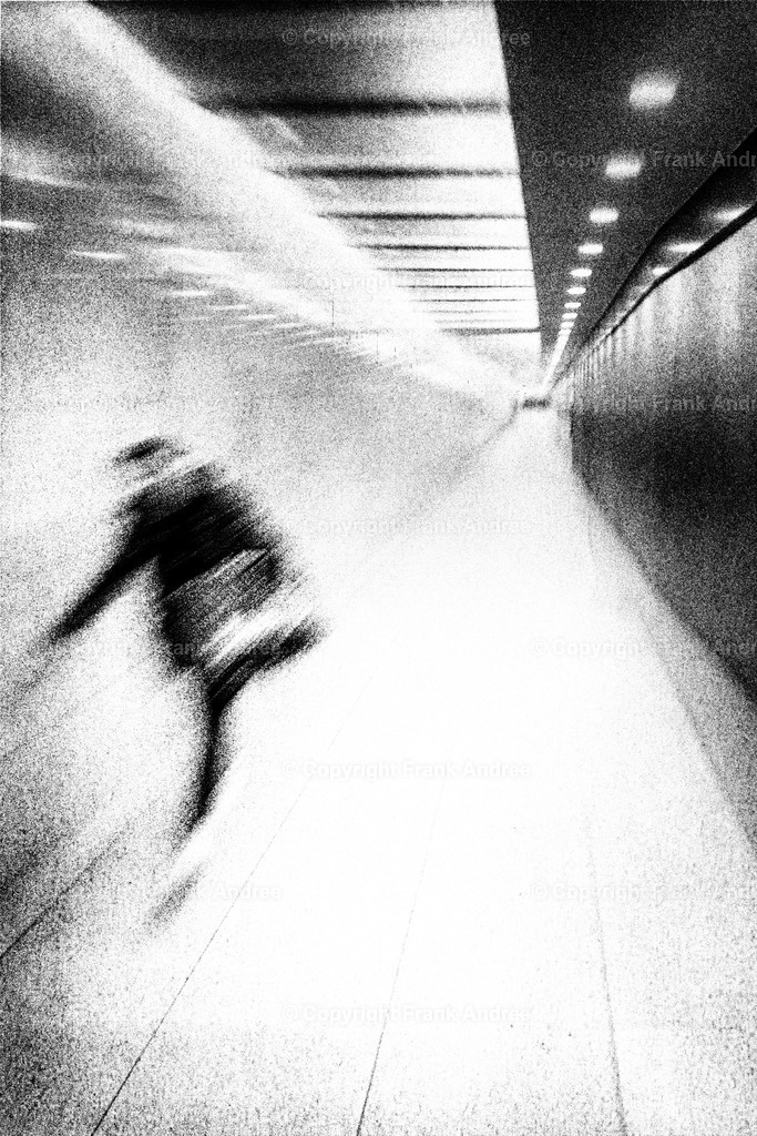 Eile | Eine junge Frau geht eilig durch einen langen Fußgängertunnel in Berlin. Abstrakte Straßenfotografie aus Berlin in schwarz und weiß - Realisiert mit Pictrs.com