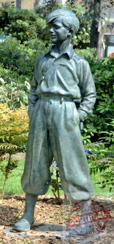 Bronze boy sculpture standing outdoors in park | Bronze boy statue with hands in pockets standing amidst green foliage in a public park - Realisiert mit Pictrs.com