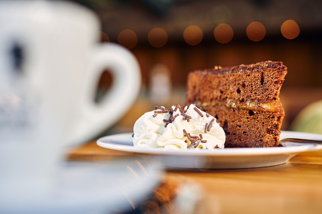 Luftburg Kolarik, eine Sachertorte mit Schlagobers | WIen, Austria - February 24, 2022; Luftburg Kolarik, eine Sachertorte mit Schlagobers auf dem Tisch stehend, daneben eine Kaffeetasse. - Realisiert mit Pictrs.com