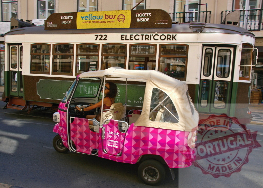 Woman driving pink tuk-tuk in Lisbon with Electri'Cork tram in background | Tourist driving pink tuk-tuk on sunny Lisbon street, passing by a vintage Electri'Cork tram - Realized with Pictrs.com