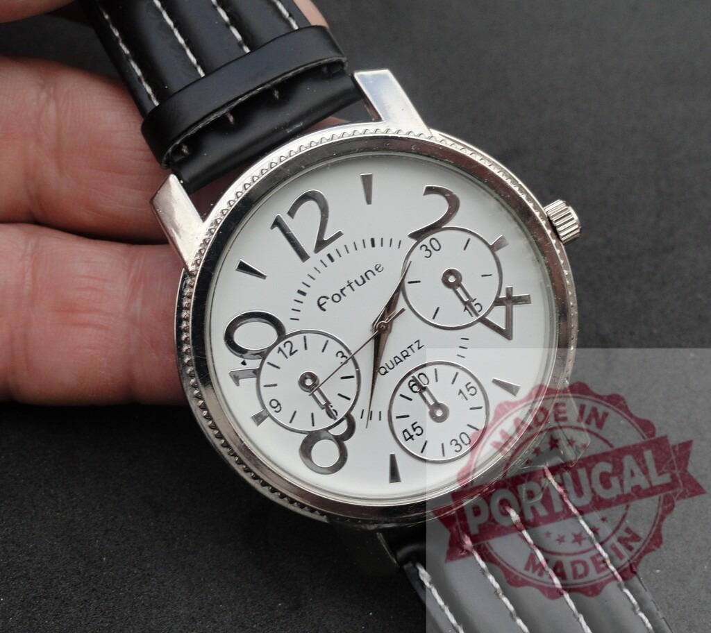 Hand holding Fortune quartz watch with black leather strap | Hand holding a white dial Fortune quartz wristwatch with a black stitched leather strap - Realized with Pictrs.com