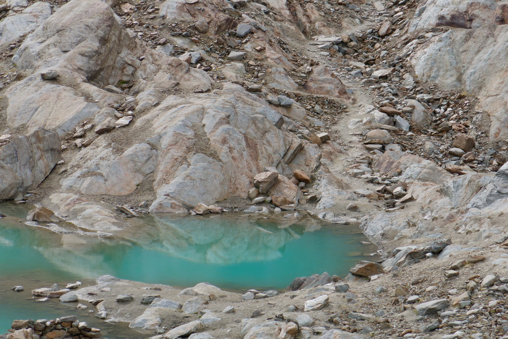 Türkisfarbener Teich oberhalb der Baumgrenze | Blauer Himmel spiegelt sich im Teich aus Gletscherwasser oberhalb der Baumgrenze - Realisiert mit Pictrs.com