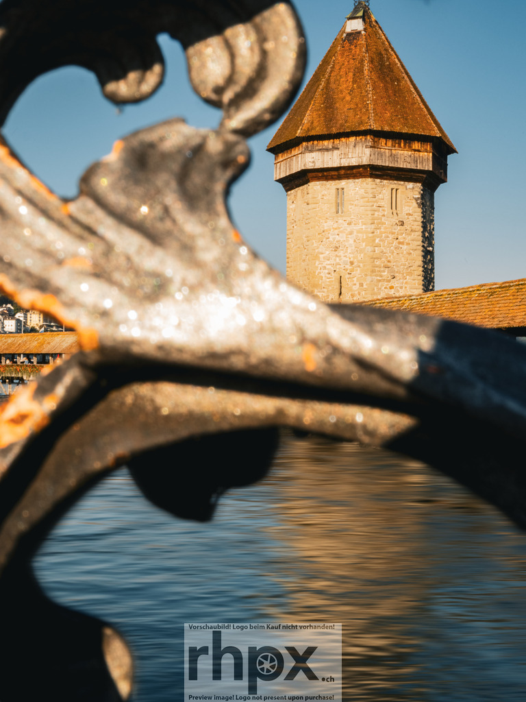 Kapellbrücke Luzern Fokus | <p><strong>Geschichte. Rahmen. Klarheit.</strong></p>
<p>Der Blick durch das schmiedeeiserne Ornament lenkt den Fokus direkt auf den historischen Wasserturm und die hölzerne Kapellbrücke. Die kräftigen Farben des Wassers und der Architektur fangen die zeitlose Atmosphäre der Stadt Luzern perfekt ein. Ein Spiel aus Form und Tradition.</p>
<p>Wähle unter "Produktauswahl" dein Wunschformat: Vom klassischen Wandbild über Puzzle & Tassen bis zum digitalen Download (z.B. als Handy-Hintergrund).</p> - Realisiert mit Pictrs.com