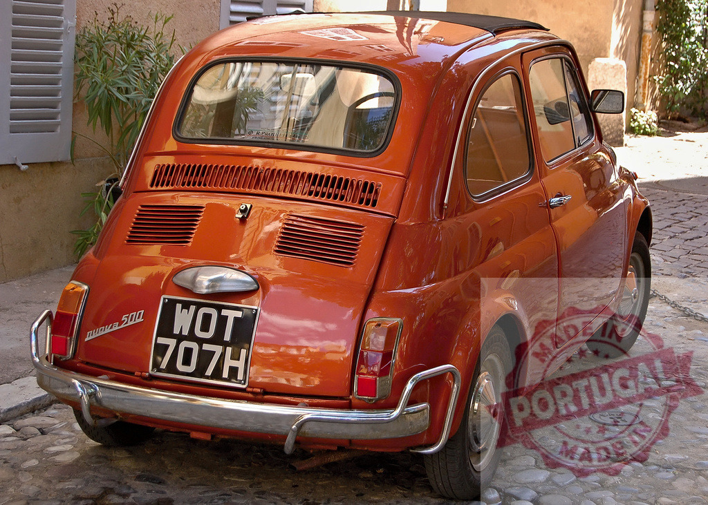 Vintage orange Fiat 500 parked on mediterranean cobblestone street | Classic Italian Fiat 500 in bright orange finish showcases iconic retro design on traditional cobblestone pavement - Realized with Pictrs.com