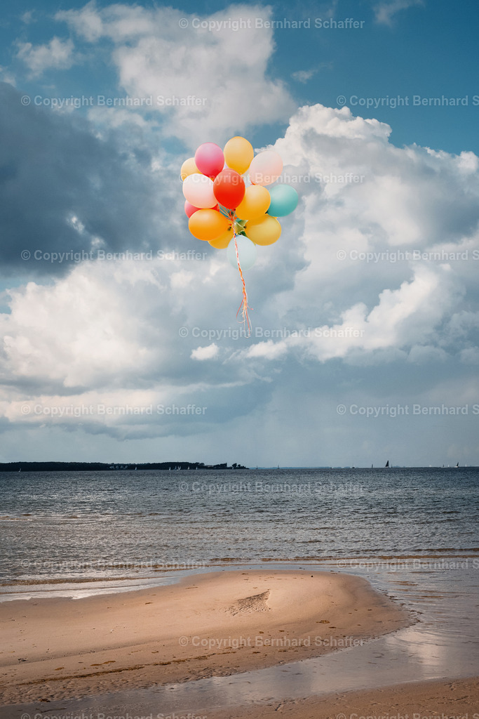 Balloons über Strand | Ein Bund bunter, losgelöster Luftballons schwebt über einem Strand an der Ostsee. - Realisiert mit Pictrs.com