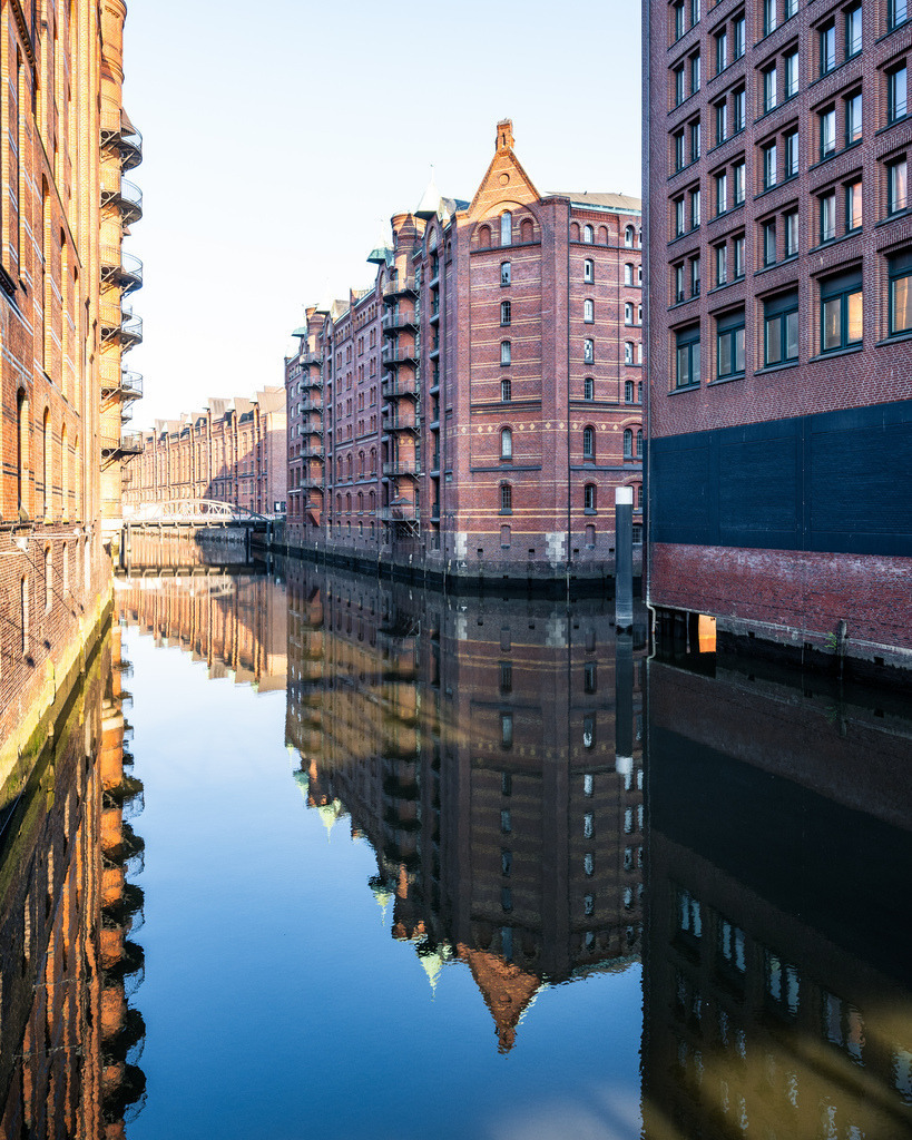 Fleet in der Speicherstadt | Geradliniger Blick durch ein Fleet in der Hamburger Speicherstadt mit ruhigem Wasser und typischer Backsteinarchitektur. - Realisiert mit Pictrs.com