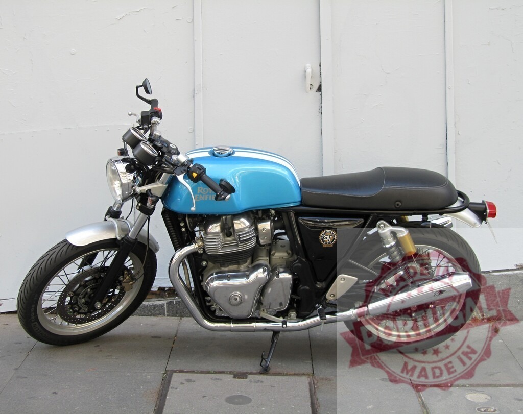 Royal Enfield Continental GT 650 motorcycle parked on sidewalk | Light blue and black Royal Enfield Continental GT 650 motorcycle parked on the sidewalk in front of a white garage door - Realized with Pictrs.com