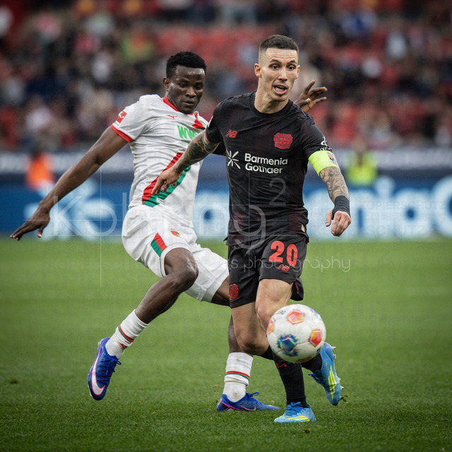 German Bundesliga, Bayer 04 Leverkusen vs. FC Augsburg, 18.04.2026 | LEVERKUSEN, GERMANY - APRIL 18, 2026 :  Alejandro Grimaldo (Bayer 04 Leverkusen, 20), Uchenna Ogundu (FC Augsburg, 39) during the German Bundesliga match on gameday 30 between Bayer 04 Leverkusen vs. FC Augsburg at BayArena on April 18, 2026 in Leverkusen, Germany. DFL REGULATIONS PROHIBIT ANY USE OF PHOTOGRAPHS AS IMAGE SEQUENCES AND/OR QUASI-VIDEO.