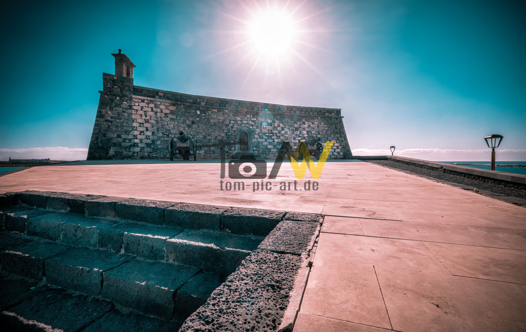 Das Castillo de San José in Arrecife, Lanzarote,Spanien | Das Bild zeigt das Castillo de San José in Arrecife, Lanzarote, Spanien. Die Festung, auch bekannt als „Festung des Hungers“, wurde unter Karl III. zur Verteidigung der Insel erbaut. Heute beherbergt die Burg das Internationale Museum für zeitgenössische Kunst (MIAC). Die Öffnungszeiten variieren je nach Wochentag. Eine ähnliche Festung, das Castillo de San Gabriel, befindet sich ebenfalls in der Bucht von Arrecife und diente ursprünglich dem Schutz vor Piraten.  - Realisiert mit Pictrs.com