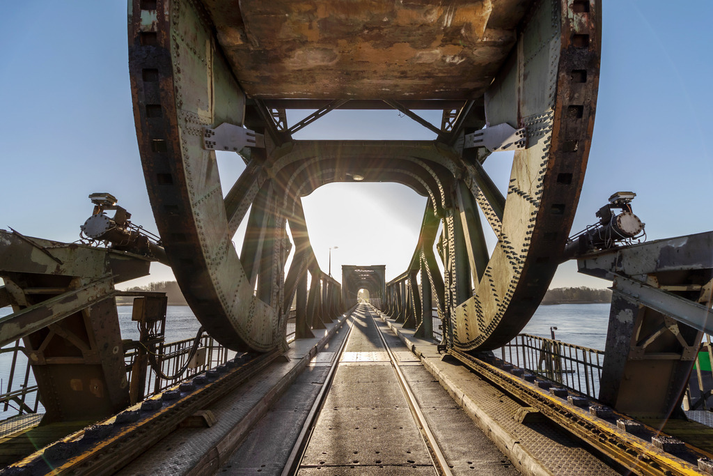 Wandbild: Lindaunisbrücke im Sonnenschein | Dieses Wandbild im Querformat zeigt die alte Schleibrücke in Lindaunis im morgendlichen Sonnenlicht. Der Himmel ist wolkenlos blau.  - Realisiert mit Pictrs.com