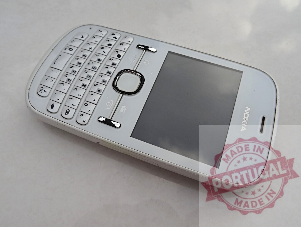 White Nokia Asha 302 mobile phone showing blank screen | White Nokia Asha 302 mobile phone showing blank screen lying on a white surface - Realized with Pictrs.com