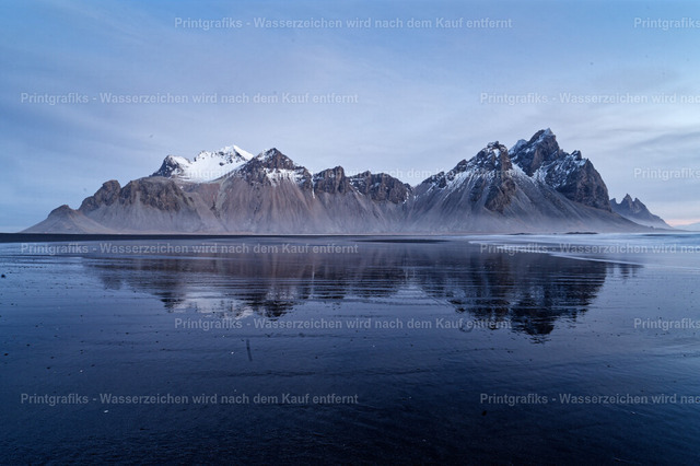Vestrahorn im stillen Morgenlicht | Die markante Bergkette des Vestrahorn spiegelt sich in der ruhigen Wasserfläche am schwarzen Strand von Stokksnes in Island. Die kühle Lichtstimmung, die klare Spiegelung und die dramatische Silhouette der Berge erzeugen eine stille, nordische Atmosphäre. - Realisiert mit Pictrs.com