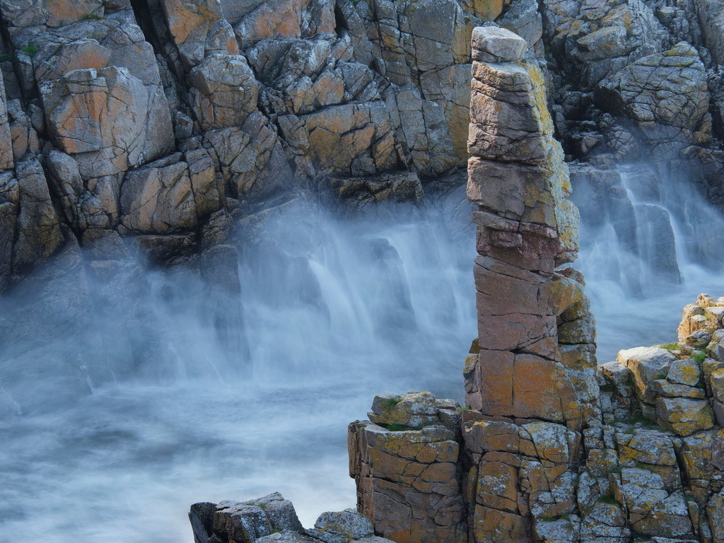 Felsnadel an der Küste mit aufschäumender Gischt | Eine große Welle ergießt sich in ein Küstental (Langzeitbelichtung) - Realisiert mit Pictrs.com