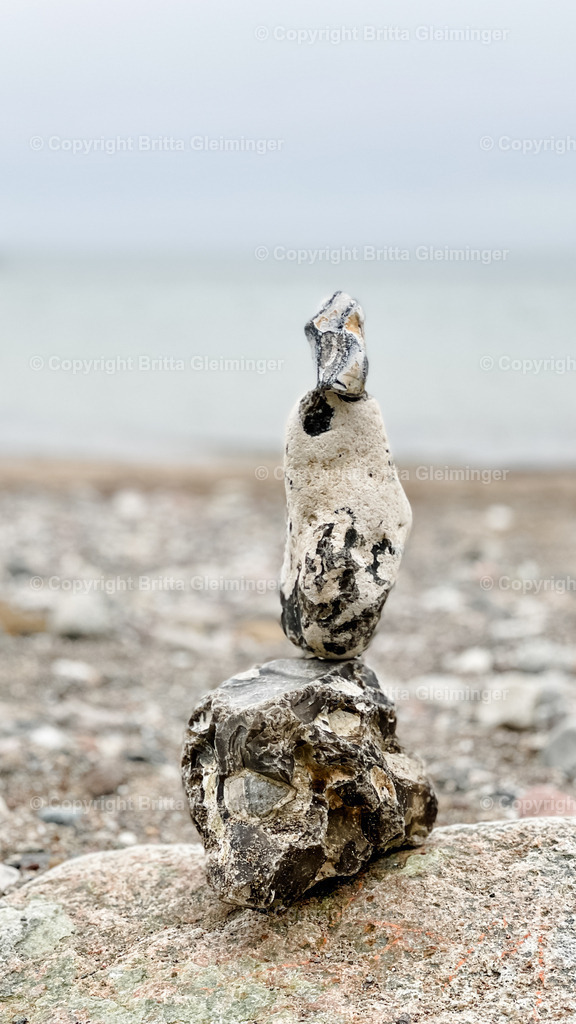 Steine am Meer | Ein kleiner Turm aus Steinen auf einem Felsen am Meer. - Realisiert mit Pictrs.com